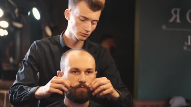 Barber curls clients moustache after beard styling — Stock Video