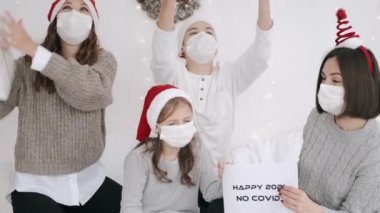 Parti şapkalı ve maskeli neşeli aile yeni yılı kutluyor.