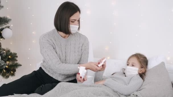 Pretty woman and daughter in masks curing at home — Stock Video