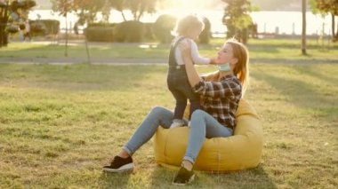 Anne ve küçük kızı güneşli havada parkta eğleniyorlar.