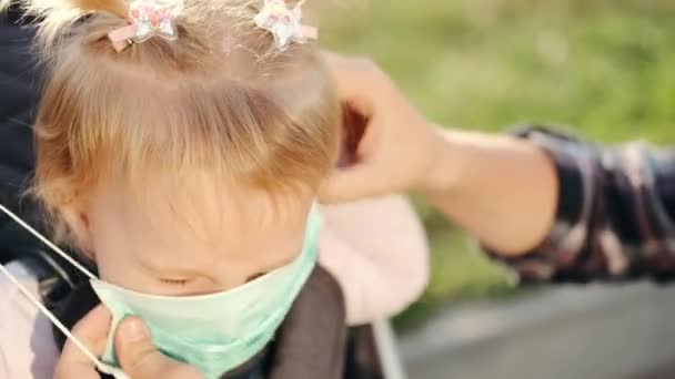 Europejska matka zakłada maskę ochronną na twarz córek w wózku — Wideo stockowe