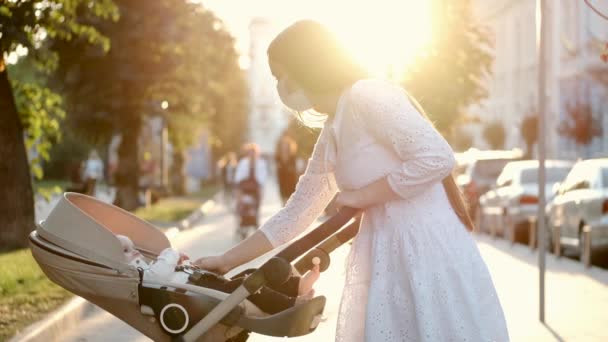 Mooie moeder lopen kijken naar baby in een wandelwagen op de stoep — Stockvideo