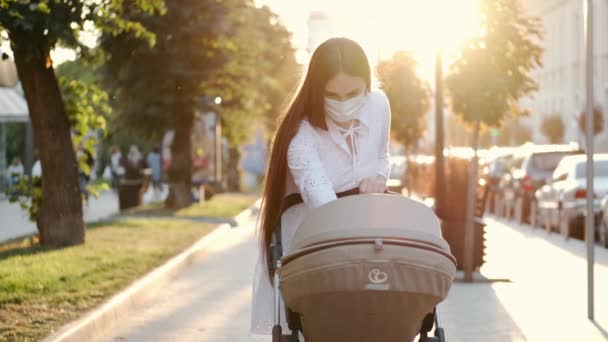 Linda madre caminando con un cochecito en el pavimento al atardecer — Vídeo de stock