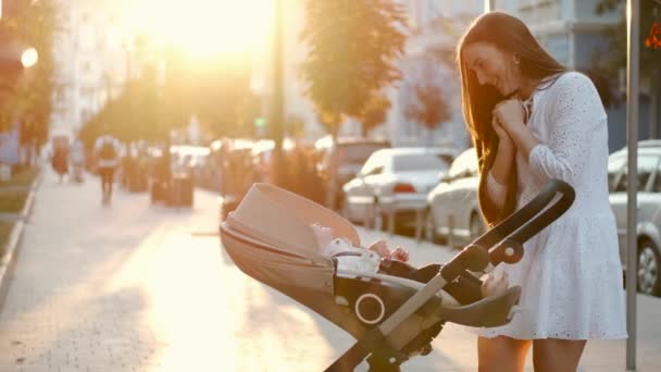 Linda madre caminando mirando al bebé en un cochecito en el pavimento — Vídeos de Stock