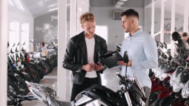 Müşteri danışmanıyla motosiklet hakkında konuşuyor.