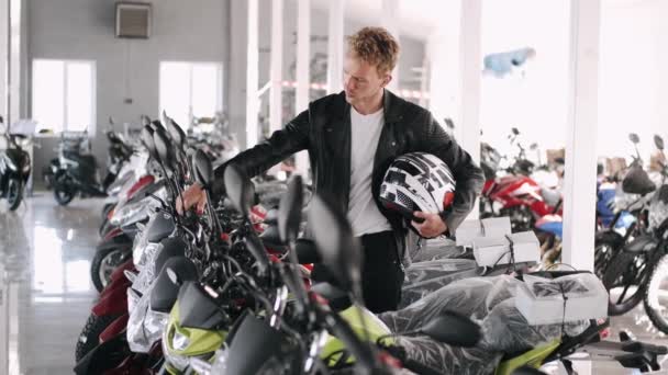 Joven hombre eligiendo moto en una tienda — Vídeos de Stock