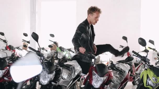 Ung mand vælger motorcykel i en butik – Stock-video
