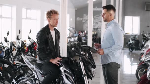 Customer talks with consultant about the motorbike — Stock Video