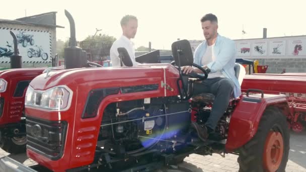 Привабливий чоловік купує трактор у відкритому магазині — стокове відео