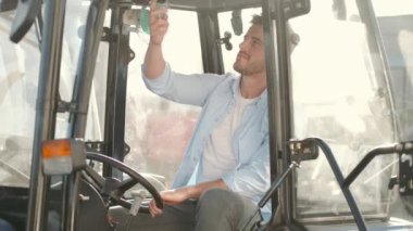 Genç yakışıklı adam traktör kulübesini kontrol ediyor.