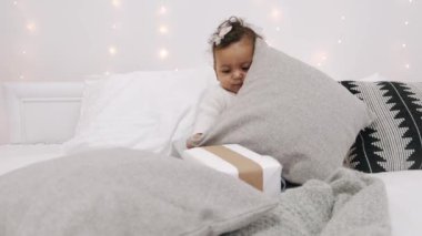 Süslü beyaz bir odada, yatağın üzerinde oynayan küçük tatlı bir kız.