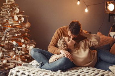 Noel ağacının yanında oturan zarif bir çift.