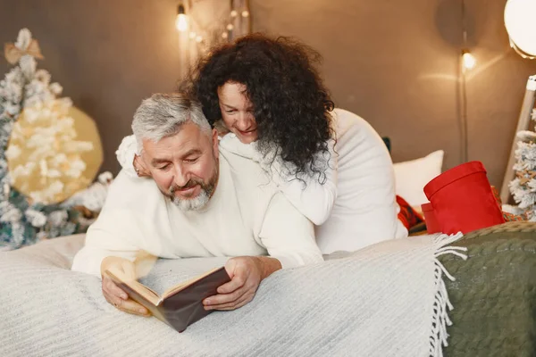 Seniorenpaar mit Geschenken sitzt auf einem Bett — Stockfoto