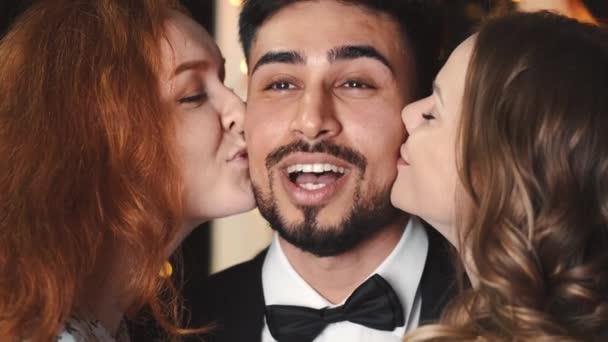Happy multikulturní přátelé políbit překvapeného muže na novoroční párty