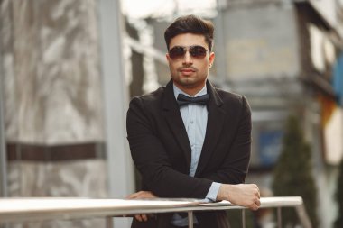 Siyah takım elbiseli şık bir işadamı dışarıda bekliyor.