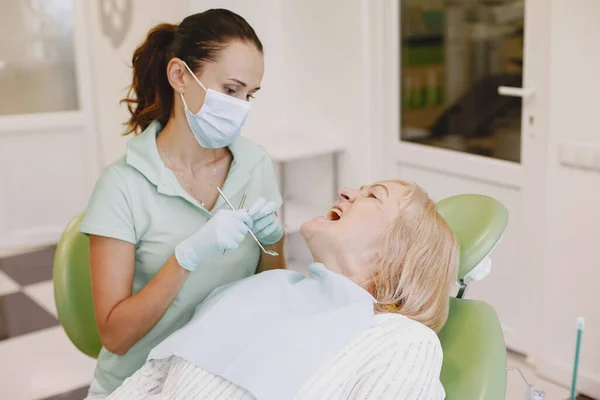 Zahnärztin sucht ihre alte Patientin mit Werkzeug — Stockfoto