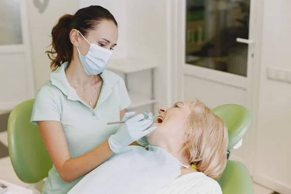 Dentista cercando il suo vecchio paziente con gli strumenti — Foto Stock