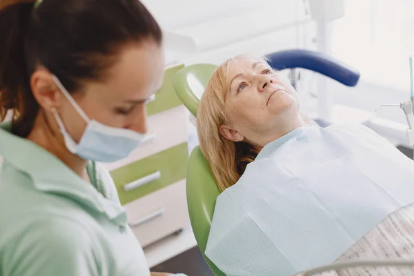 Zubař hledá svého starého pacienta s nástroji — Stock fotografie