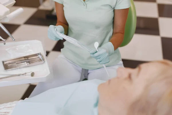 Dentysta patrząc jej stary pacjent z narzędziami — Zdjęcie stockowe