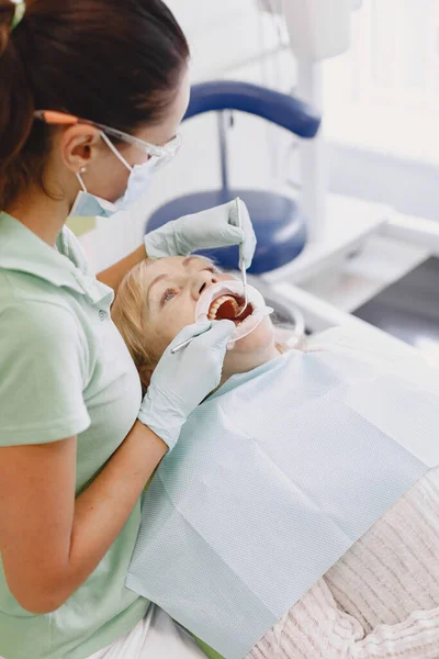 Dentista mirando a su viejo paciente con herramientas —  Fotos de Stock