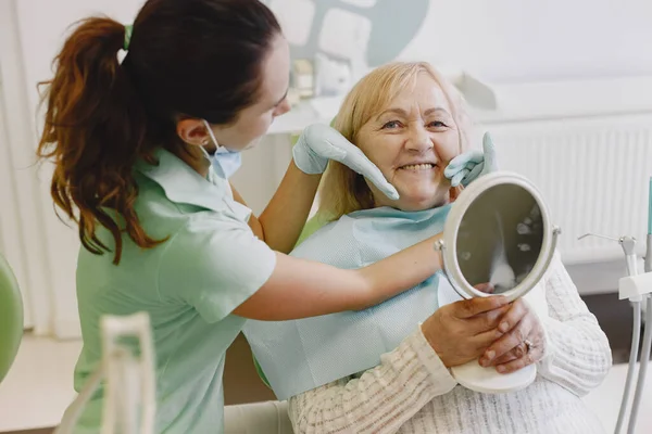 Dentista cercando il suo vecchio paziente con gli strumenti — Foto Stock