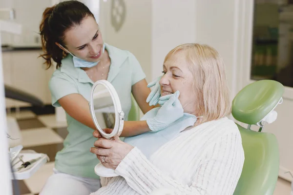 Dentista cercando il suo vecchio paziente con gli strumenti — Foto Stock