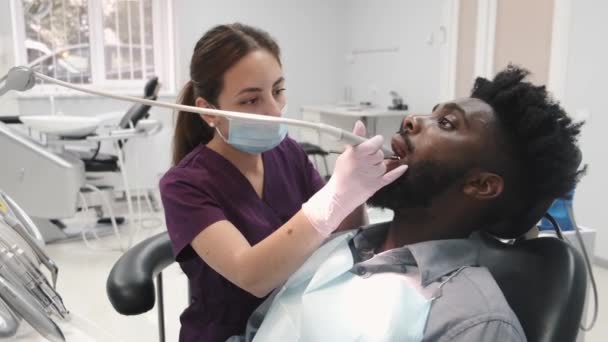 Dentista examinando los dientes de un paciente en el consultorio del dentista — Vídeo de stock