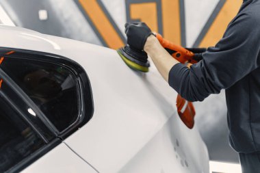 Adam garajda araba cilalıyor.