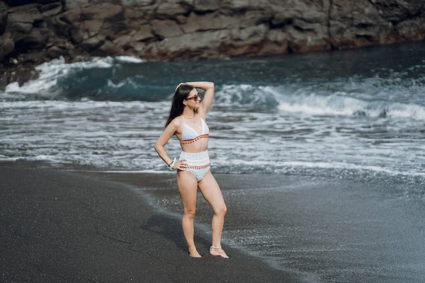 La ragazza in un costume da bagno elegante ha un riposo su una spiaggia — Foto Stock