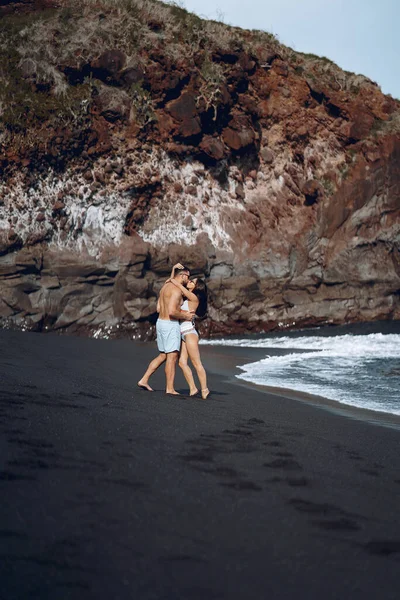 Elegante coppia su una spiaggia vicino a scogli — Foto Stock