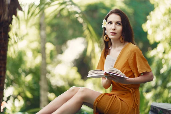 Woman sitting with a book on a jungle background — Stock Photo, Image