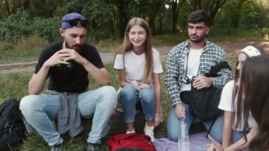 Arkadaş çevresi ormanda oturuyor ve konuşuyor.