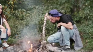 Genç yürüyüşçüler ormanda ateş yakıyor.
