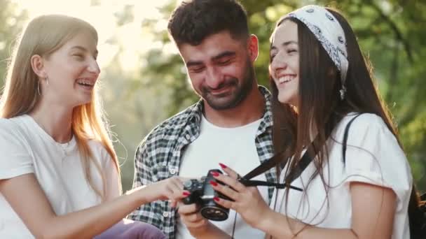 Three young people look at camera display in forest — Stock Video