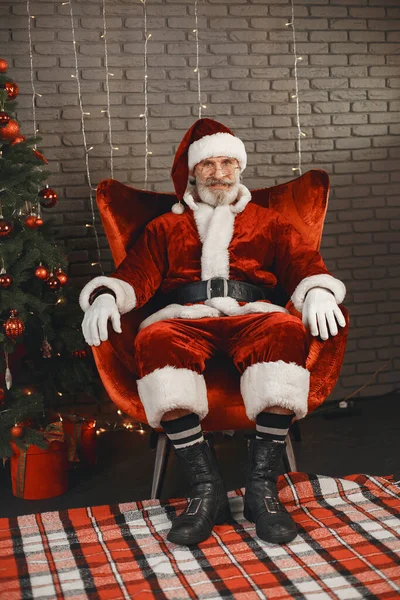 Człowiek w stroju Mikołaja siedzi na krześle — Zdjęcie stockowe
