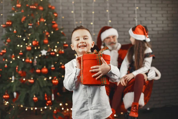 Mikołaj i dzieci wokół ozdobionej choinki — Zdjęcie stockowe