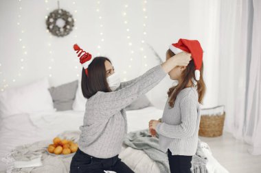 Anne ve küçük kızı evde tıbbi maske takıyor.