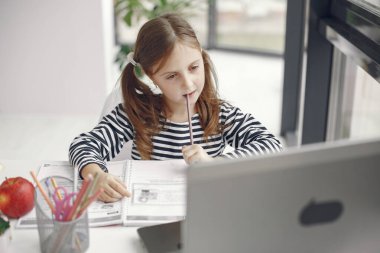 Evde bilgisayarını kullanarak internetten ders çalışan küçük bir kız.