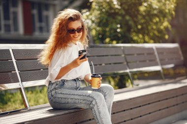 Öğrenciler telefon ve kahveyle şehirde oturuyorlar.