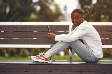 Beyaz kazaklı siyah bir adam yaz şehrinde