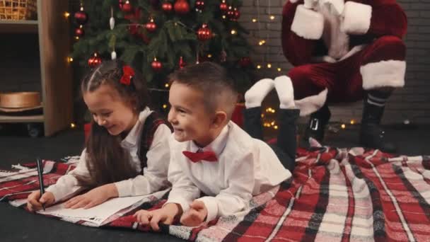 Barn skriver brev till Santa på jul och Santa på bakgrunden — Stockvideo