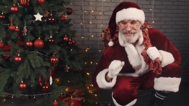 Santa claus sitter tyst nära xmas träd och kommer att göra överraskning för barn — Stockvideo