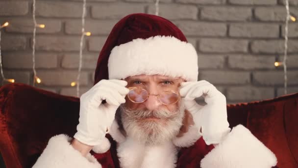 Nahaufnahme eines ernsthaften Weihnachtsmannes, der seine Brille hält — Stockvideo