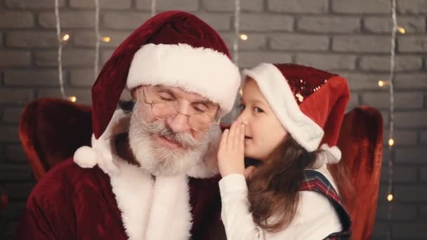 Fille en chapeau rouge chuchotant un souhait de Père Noël — Video