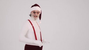 Gülümseyen gri saçlı Noel Baba şapkalı ve pantolon askılı adam vak arka plan stüdyosunda izole edilmiş..