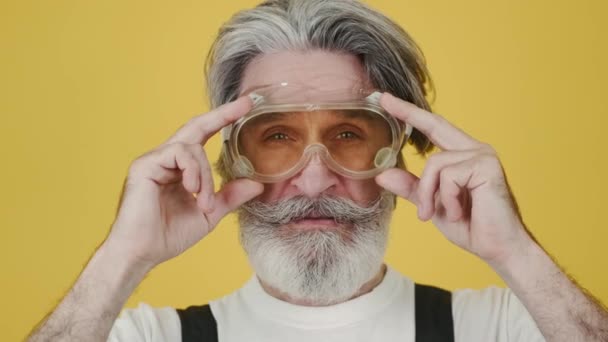 Homme à tout faire senior portant des lunettes de protection sur fond jaune — Video
