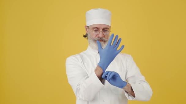 医療用帽子の男は使い捨て手袋をコピースペースに置きます — ストック動画