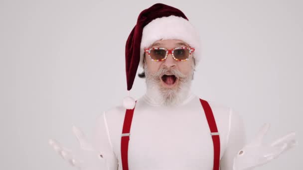 Lächelnder grauhaariger Weihnachtsmann mit Weihnachtsmütze und Hosenträgern auf weißem Hintergrund. — Stockvideo
