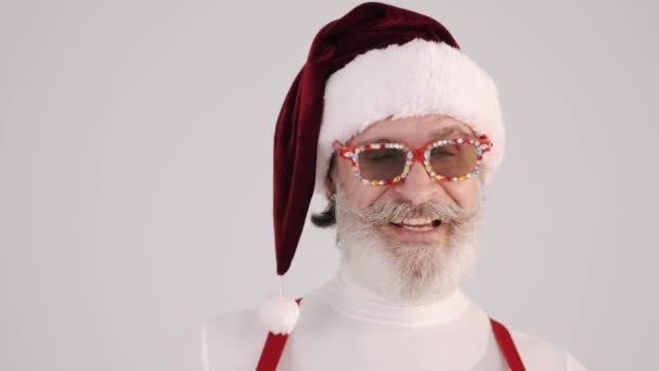 Lächelnder grauhaariger Weihnachtsmann mit Weihnachtsmütze und Hosenträgern auf weißem Hintergrund. — Stockvideo