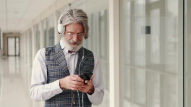 Kulaklıklı hippi işadamı akıllı telefonuyla müzik dinliyor.